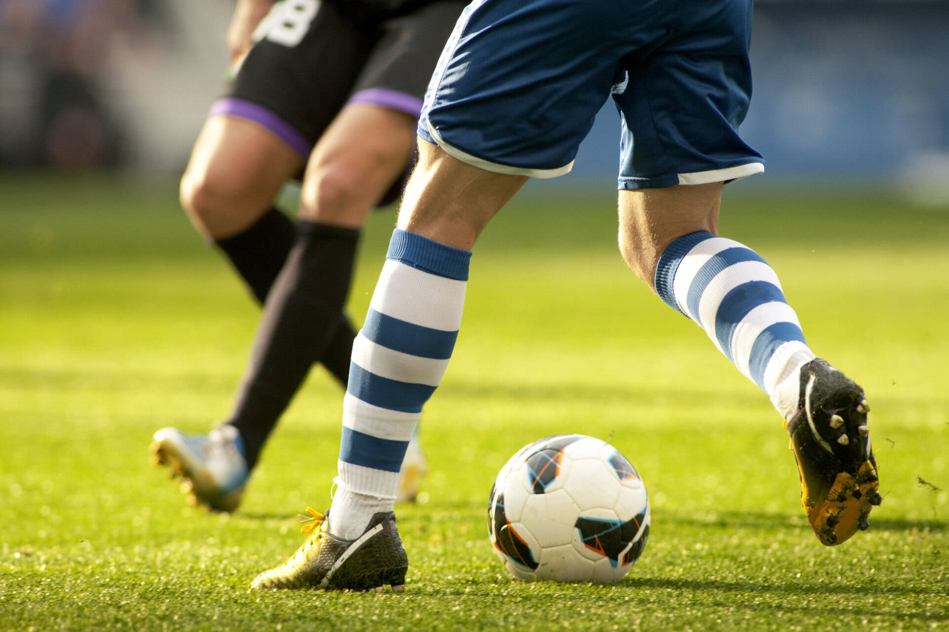 Legs of two soccer players vie on a match
